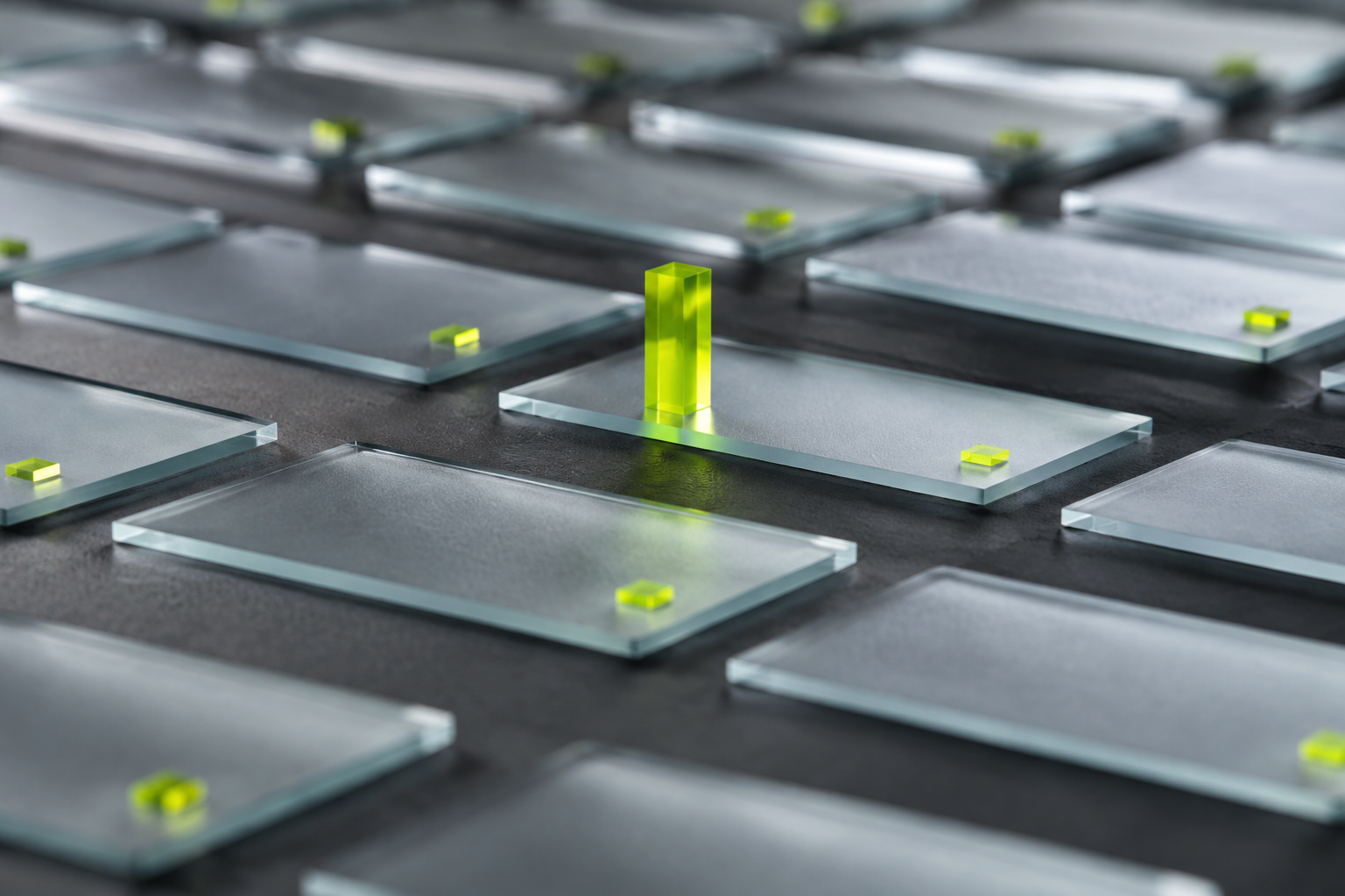 A lime signal stands in focus among a grid of softly blurred glass panels.